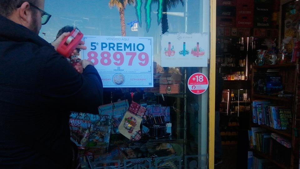 Un trabajador de Loterían coloca el cartel anunciador del quinto premio 88979 en el estanco «Quirós» (C.A.)