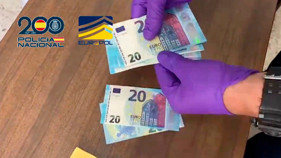 Un agente manipula algunos de los billetes falsos intervenidos a la organización (POLICÍA NACIONAL)