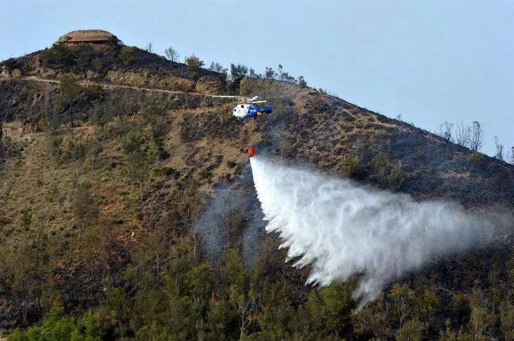 Helic&oacute;ptero sobrevolando y descargando sobre llamas