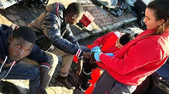 Una voluntaria de Cruz Roja atiende a dos migrantes en una imagen de archivo (C.A./ARCHIVO)