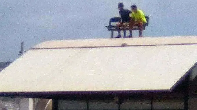 Dos menores, sentados sobre el techo de un edificio de la estaci&oacute;n mar&iacute;tima (C.A./ARCHIVO)