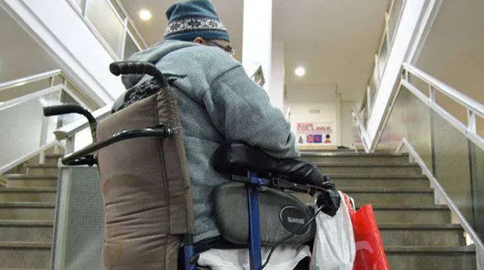 Una persona en silla de ruedas enfrentada al obst&aacute;culo de una escalera (C.A.)
