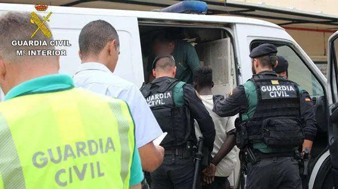 Uno de los detenidos en el CETI es conducido a un furg&oacute;n policial (GUARDIA CIVIL)
