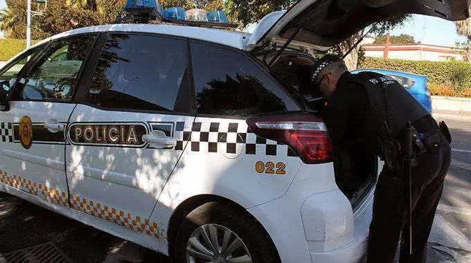 Un agente de la Polic&iacute;a Local, junto a un coche patrulla (C.A.)