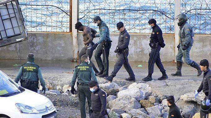 Guardias civiles conducen a un migrante que acaba de saltar la valla en el tramo de Benzú (C.A./ARCHIVO)