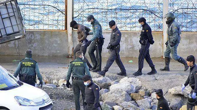 Guardias civiles conducen a un migrante que acaba de saltar la valla en el tramo de Benz&uacute; (C.A./ARCHIVO)