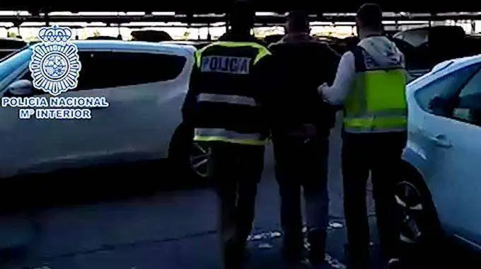 Dos agentes conducen al detenido a un coche policial (POLIC&Iacute;A NACIONAL)