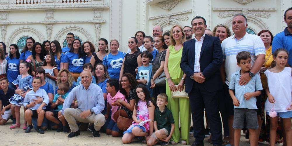 Familiares y pequeños de la Asociación de Autismo posan con miembros del equipo de gobierno ante la portada de Feria (C.A.)