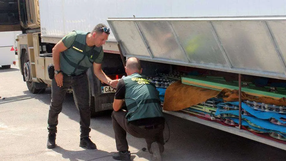 Dos agentes de la Guardia Civil inspeccionan los bajos de un cami&oacute;n (C.A.)