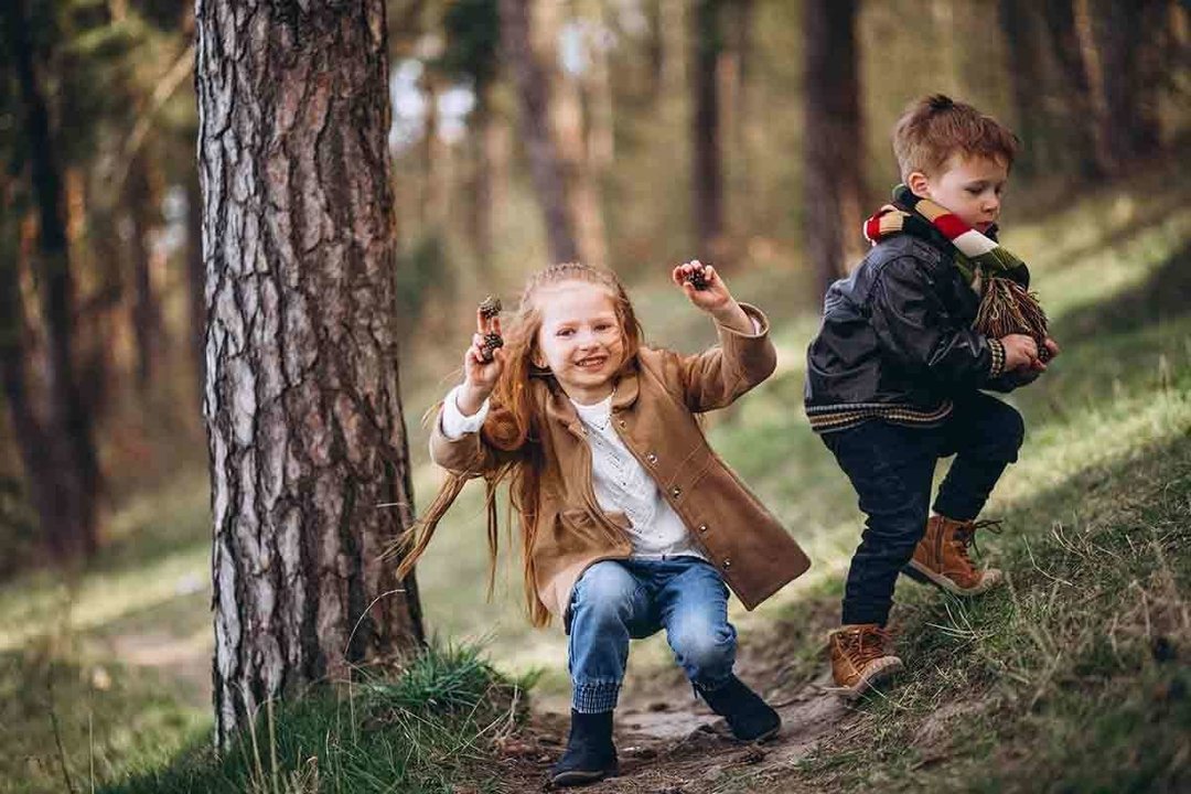 Girl with her little brother together in forest