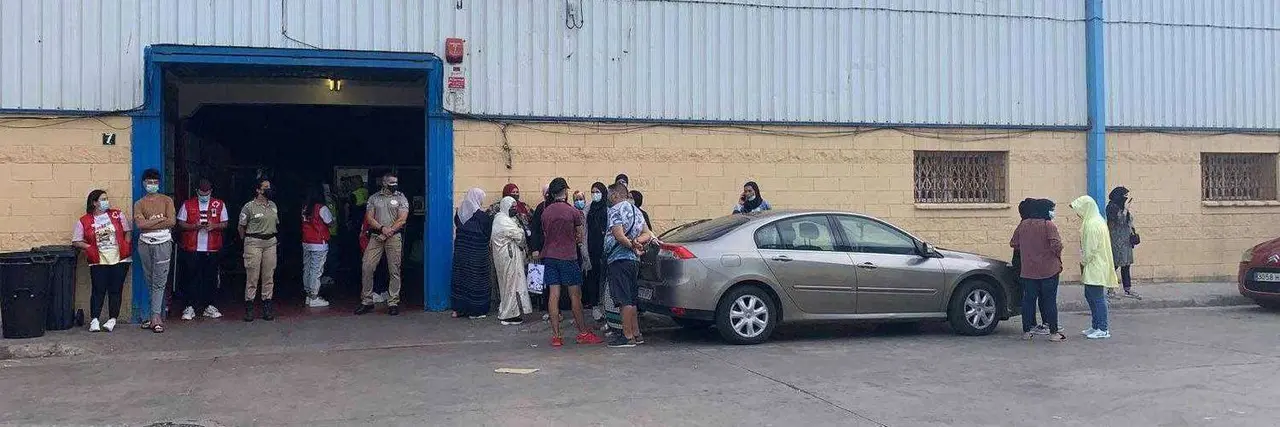Marroqu&iacute;es a las puertas de la nave de El Tarajal, en una imagen tomada esta tarde (C.A.)