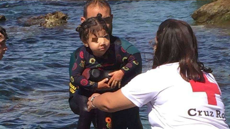 Una niña es rescatada del agua por un agente de la Guardia Civil en Ceuta (MINISTERIO DEL INTERIOR)