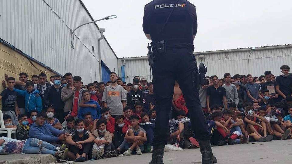 Un policía, junto a un grupo de migrantes en el polígono de El Tarajal (CEDIDA)