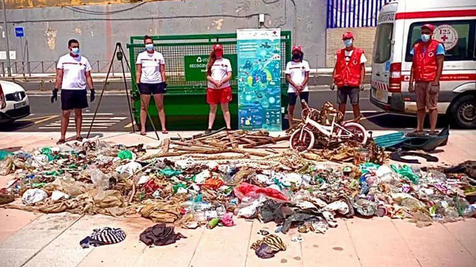 Voluntarios de Cruz Roja posan junto a los residuos extra&iacute;dos de la playa (CEDIDA)