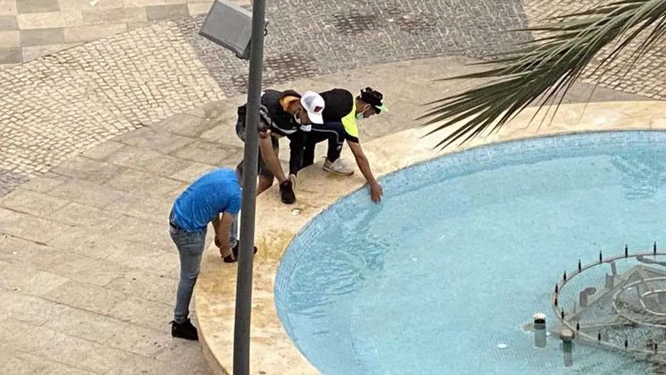 Tres j&oacute;venes migrantes se refrescan en una fuente p&uacute;blica (C.A./ARCHIVO)