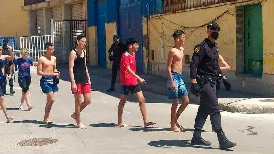 Un agente conduce a un grupo de menores en el recinto del pol&iacute;gono de El Tarajal (C.A./ARCHIVO)