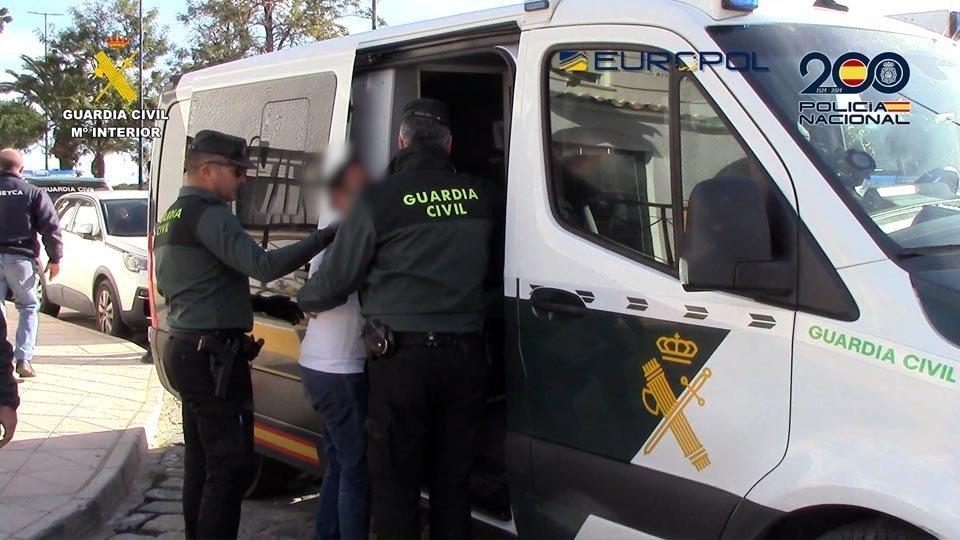 Agentes de la Guardia Civil introducen a uno de los detenidos en un vehículo policial (MINISTERIO DEL INTERIOR)