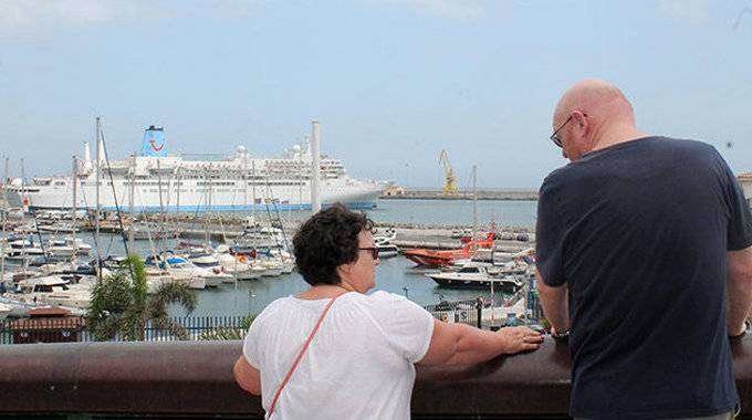 Dos turistas charlan frente al crucero que les ha traído a la ciudad (C.A./ARCHIVO)