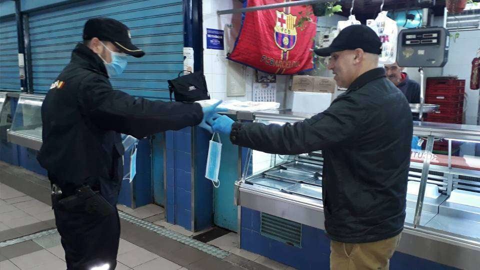 Un agente de la Policía Nacional entrega una mascarilla a un ciudadano