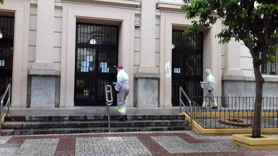 Dos operarios desinfectan la fachada del edificio de Correos (J. CHELLARAM)