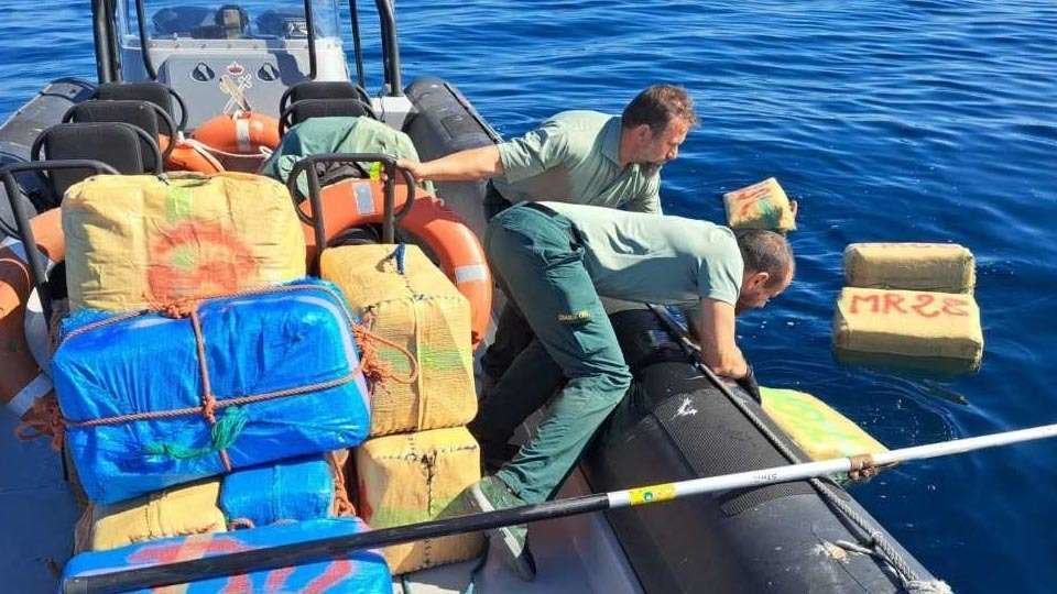 Dos agentes recuperan del mar algunos de los 55 fardos con droga intervenidos (GUARDIA CIVIL)
