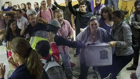 Un polic&iacute;a intenta hacerse con una urna en manos de dos mujeres. / Twitter