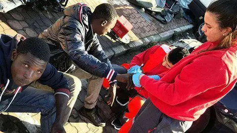 Una voluntaria de Cruz Roja atiende a dos migrantes en una imagen de archivo (C.A./ARCHIVO)
