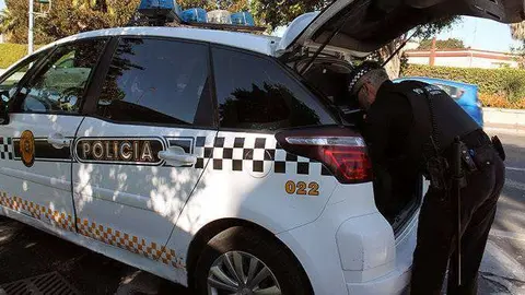 Un agente de la Polic&iacute;a Local, junto a un coche patrulla (C.A.)