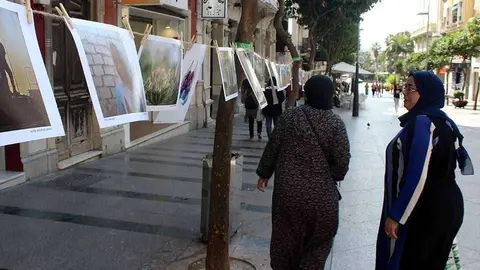 Dos viandantes se detienen a contemplar los trabajos expuestos en el Paseo del Revell&iacute;n (C.A.)