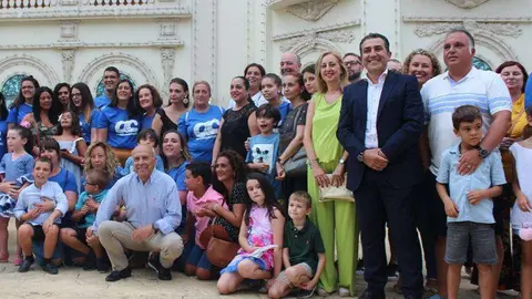 Familiares y peque&ntilde;os de la Asociaci&oacute;n de Autismo posan con miembros del equipo de gobierno ante la portada de Feria (C.A.)