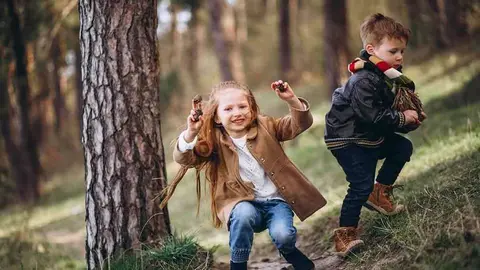 Girl with her little brother together in forest