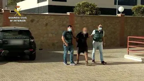 Dos agentes de la Guardia Civil conducen a uno de los detenidos en la intervenci&oacute;n policial (GUARDIA CIVIL)