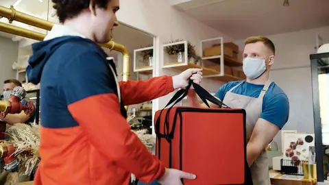  man-in-a-face-mask-handing-over-a-thermal-bag-to-another-man-4393668 