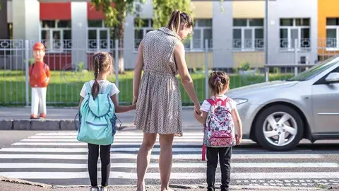 Back to school education concept with girl kids, elementary students, carrying backpacks going to class on school first day holding hand in hand together walking up building stair happily