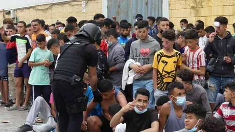 Un polic&iacute;a, junto a un grupo de menores marroqu&iacute;es en el pol&iacute;gono de El Tarajal