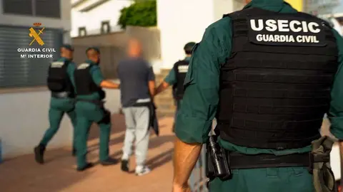 Los agentes conducen a uno de los detenidos en la operaci&oacute;n policial (GUARDIA CIVIL)