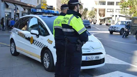 Dos agentes de la Polic&iacute;a Local, junto a un coche patrulla (C.A./ARCHIVO)