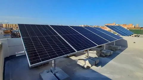 Aerial view of many photo voltaic solar panels mounted of industrial building roof.