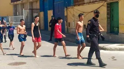 Un agente conduce a un grupo de menores en el recinto del pol&iacute;gono de El Tarajal (C.A./ARCHIVO)