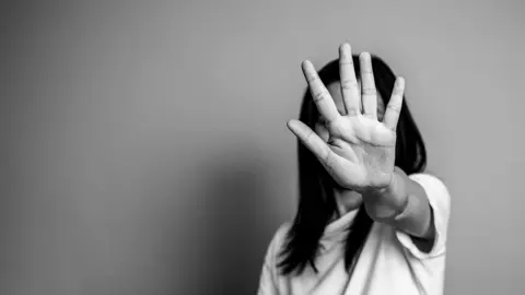 Una mujer extiende la mano en se&ntilde;al de rechazo / Getty